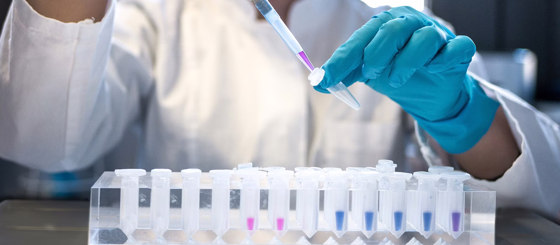 Female scientist pipetting colored chemicals into a tube